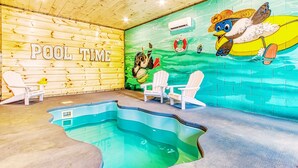 Un espace piscine agrémenté d’un mur en bois, d’une fresque murale et de deux fauteuils Adirondack.