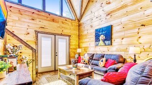 L'intérieur d'un chalet en bois chaleureux et accueillant, avec un canapé, une table basse et des coussins décoratifs.
