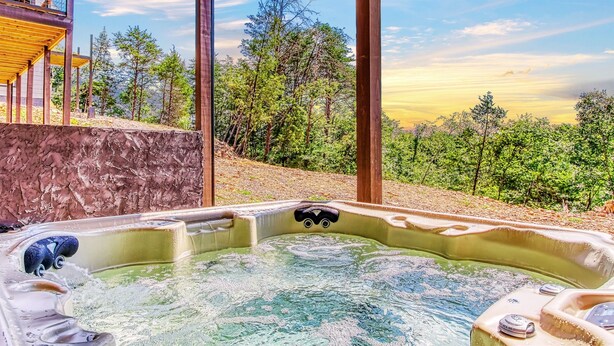 Un bain à remous avec vue sur une forêt et un bâtiment en arrière-plan.