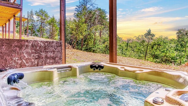 Un bain à remous avec vue sur une forêt et un bâtiment en arrière-plan.