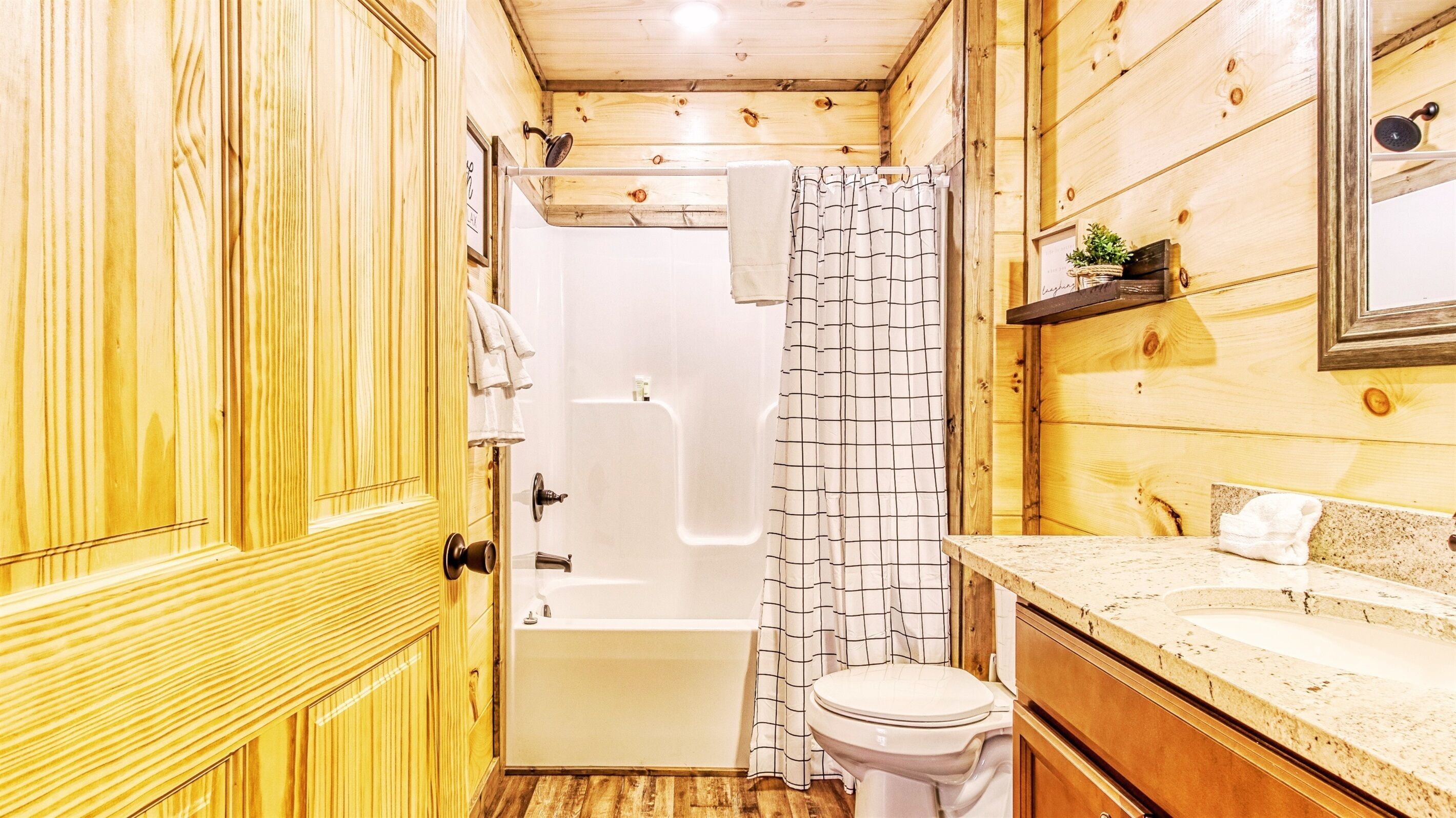Bagno di una baita in legno con doccia, WC e lavandino.