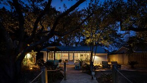 A wooden pathway leading to a building with a glass facade, surrounded by trees and a fence. - Lucky Charm by Tybee Vacation Rentals (Tybee Island)