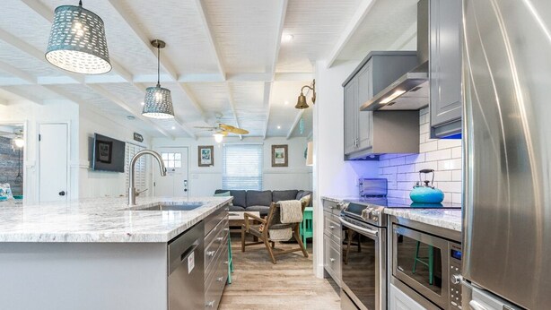 A modern kitchen with stainless steel appliances, a marble countertop, and pendant lighting. - Lucky Charm by Tybee Vacation Rentals (Tybee Island)