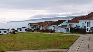 Un parc de caravanes situé sur la côte, comprenant plusieurs bâtiments de type caravane, une zone herbeuse et une allée pavée.