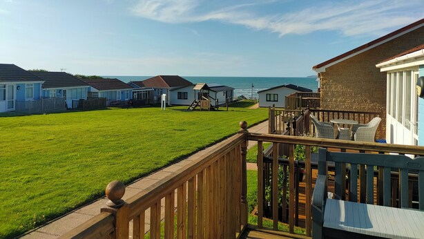 Une rangée de maisons mobiles avec une pelouse et vue sur la mer.