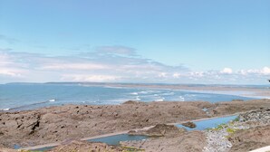 Un paysage côtier rocheux offrant une vue sur la mer et sur la terre, qui se trouve au loin.