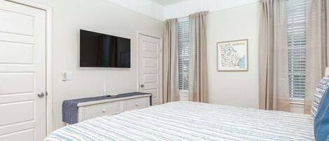 Een slaapkamer met een bed, een televisie, een kaart aan de muur en een raam met gordijnen.