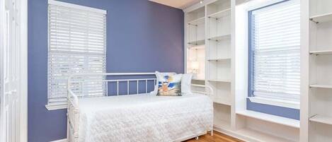 A bedroom with a bed, a ceiling fan, and built-in shelving.
