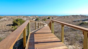 A wooden boardwalk leading to a beach with a clear sky. - Ocean Oasis by Tybee Vacation Rentals (Tybee Island)