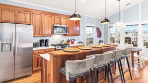 Une cuisine moderne avec des meubles en bois, des appareils électroménagers en acier inoxydable et un coin bar agrémenté de chaises en osier.