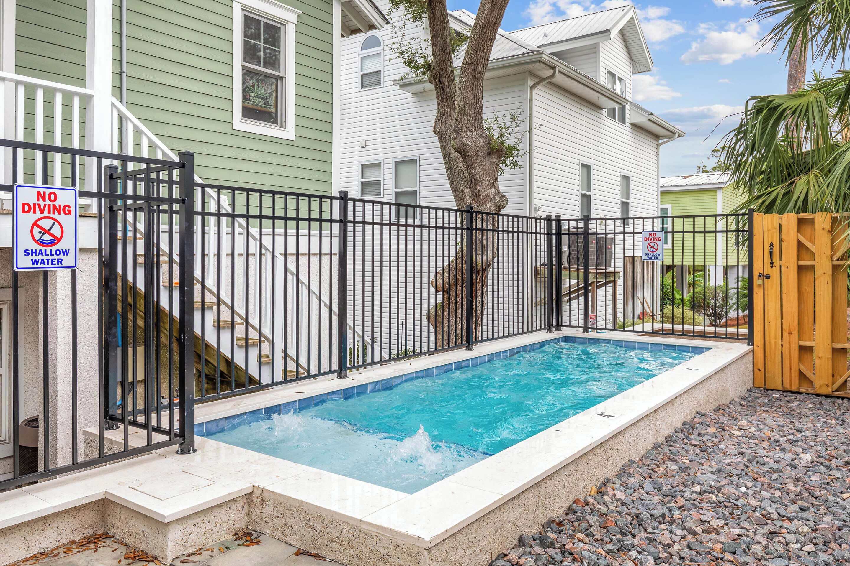 A swimming pool with a black metal fence, a no diving sign, and a no swimming sign.
