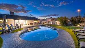 A swimming pool with lounge chairs and a covered patio area. - Upscale Oasis | Pool, Putting Green, Volley Court & Open Yard (Scottsdale)