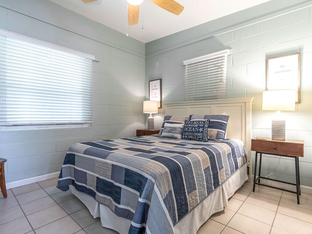 A bedroom with a large bed, a nightstand, a bedside table, and a ceiling fan.