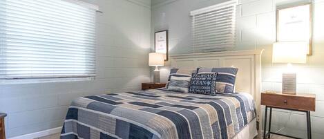 A bedroom with a large bed, a nightstand, a bedside table, and a ceiling fan.