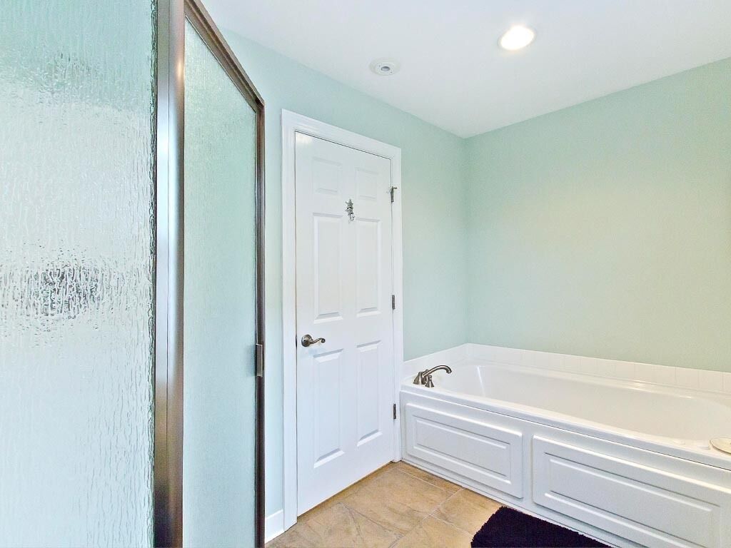 A bathroom with a white bathtub, a white door, and a light green wall.