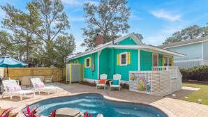 A turquoise house with a swimming pool, white deck chairs, and a fenced patio area. - Sassy Seagull by Tybee Vacation Rentals (Tybee Island)