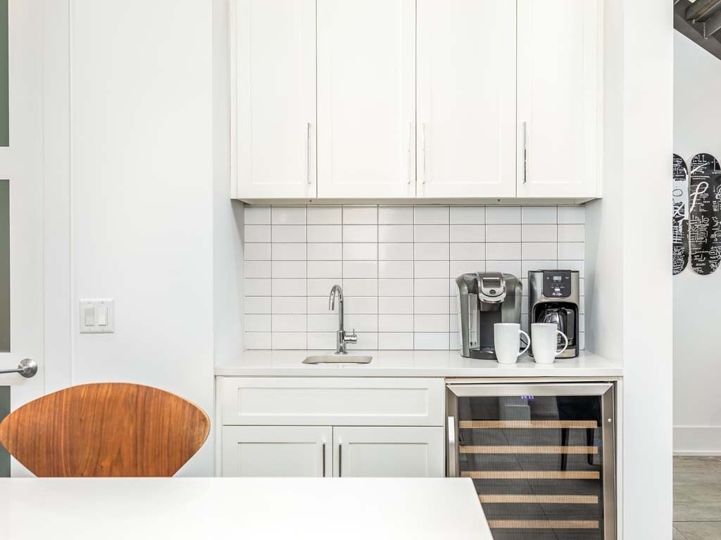 A compact kitchen with white cabinets, a sink, and a coffee machine.