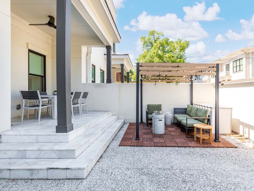 A covered patio area with outdoor seating, a pergola, and a staircase leading to the entrance.