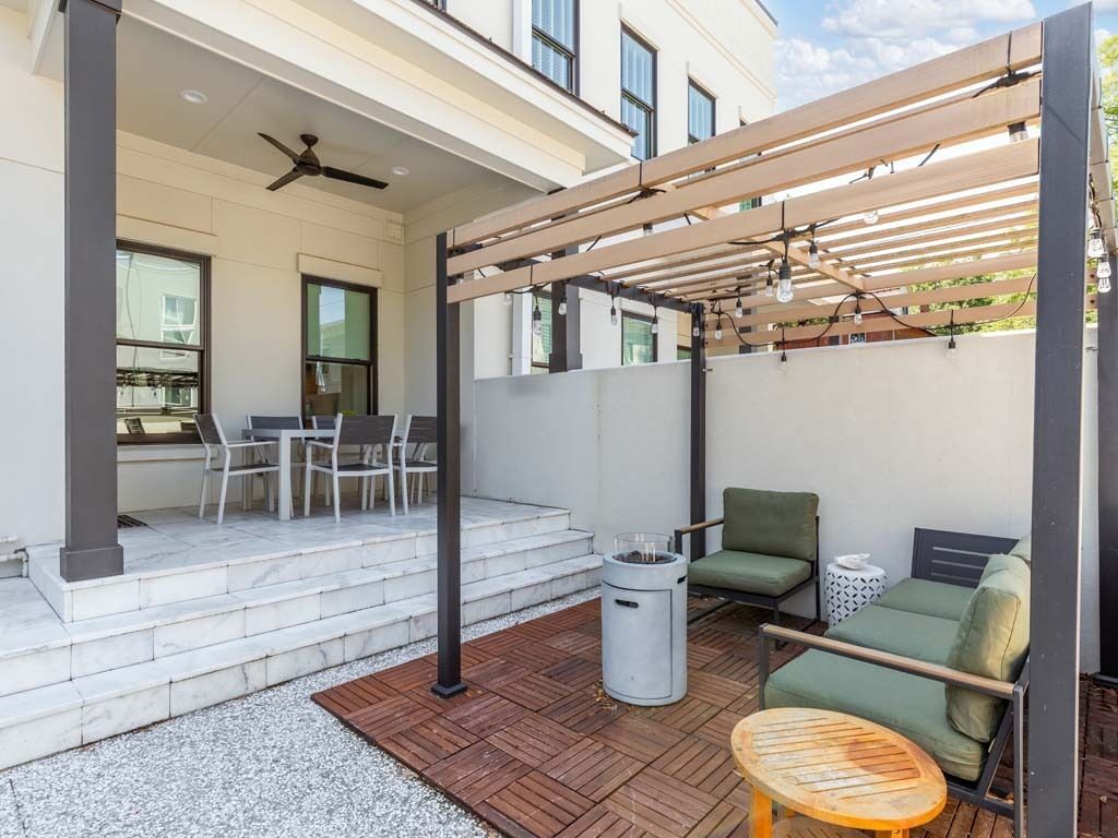 An outdoor patio area with a pergola, seating arrangements, and a fire pit.