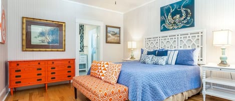 Ein Schlafzimmer mit Bett, Deckenventilator, Kommode und Bildern an den Wänden.