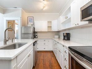 Kitchen features a double sink, refrigerator, microwave, and stove.
