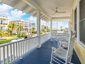 Relax in a serene outdoor space with comfortable white rocking chairs and a ceiling fan.