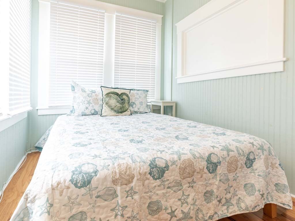 A bedroom with a bed, a nightstand, and a window with blinds.