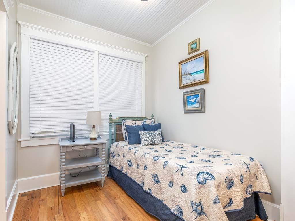 A bedroom with a bed, a nightstand, a lamp, and a window with blinds.