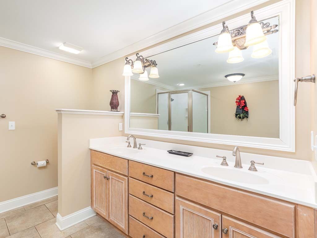 Une salle de bain avec un grand miroir, deux lavabos, des meubles en bois et un porte-serviettes.