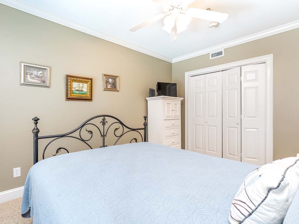 A bedroom with a bed, a wardrobe, and a ceiling fan.