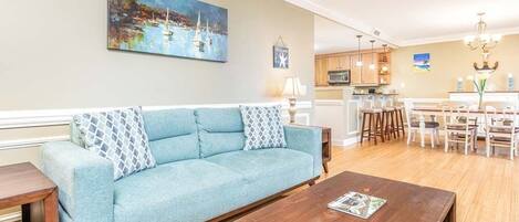 A living room with a light blue sofa, wooden coffee table, and a painting on the wall.