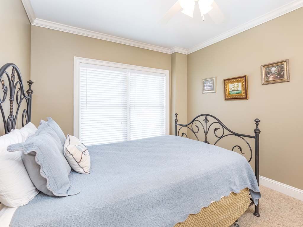 Une chambre à coucher avec un lit, une fenêtre avec des stores et deux tableaux encadrés accrochés au mur.