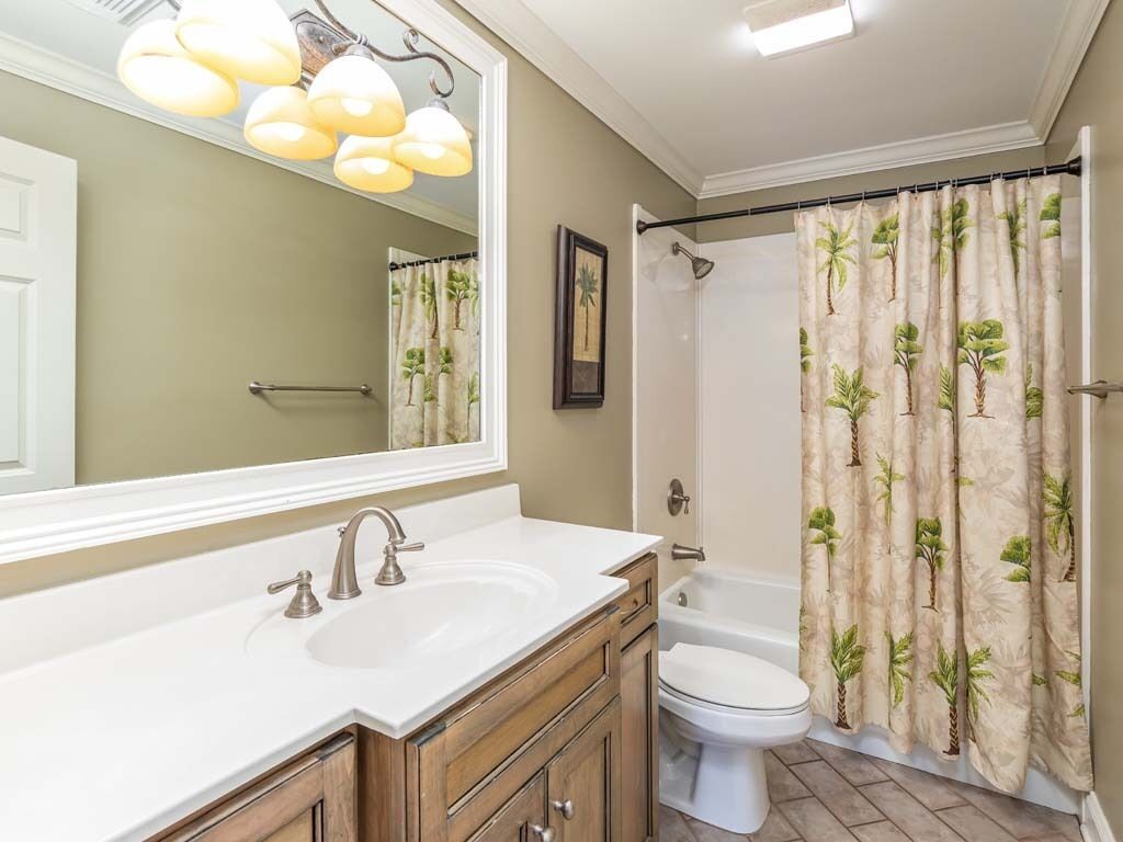 A bathroom with a sink, mirror, toilet, and shower curtain.