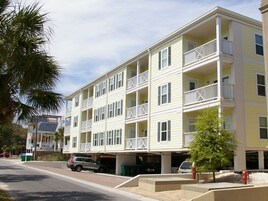 Un immeuble à plusieurs étages doté de balcons, d’un garage et d’un palmier.