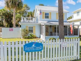 Une maison à deux étages avec un porche, un drapeau et une enseigne indiquant qu’il s’agit d’une maison de vacances à louer à Tybee Island, en Géorgie.