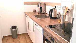 Een kleine keuken met een koffiezetapparaat, waterkoker en een ingebouwde oven.