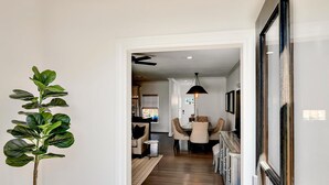 A hallway with a hanging light fixture, a potted plant, and a view into a dining area. - On Austin Ave!!! Completely remodeled and close to Magnolia, Downtown & Baylor.  (Waco)