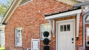 A brick building with a white door, a bench, and a small white chair on a wooden deck. - On Austin Ave!!! Completely remodeled and close to Magnolia, Downtown & Baylor.  (Waco)