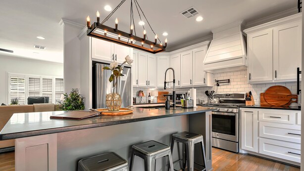 A modern kitchen with white cabinets, stainless steel appliances, and a central island with stools. - On Austin Ave!!! Completely remodeled and close to Magnolia, Downtown & Baylor.  (Waco)