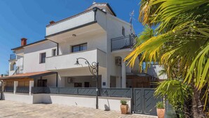 A two-story building with a balcony, a tiled roof, and a gated entrance. - Holiday apartment with sea view (Poreč)
