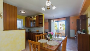 A dining area with a glass table, wooden chairs, and a chandelier. - Holiday apartment with sea view (Poreč)