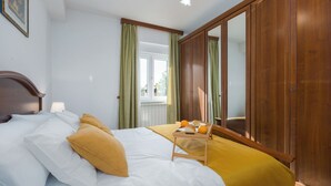 A bedroom with a bed, wooden wardrobe, and a window with curtains. - Holiday apartment with sea view (Poreč)