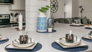 Una cocina moderna con una mesa redonda para cuatro, con manteles individuales azules y tazas de metal.