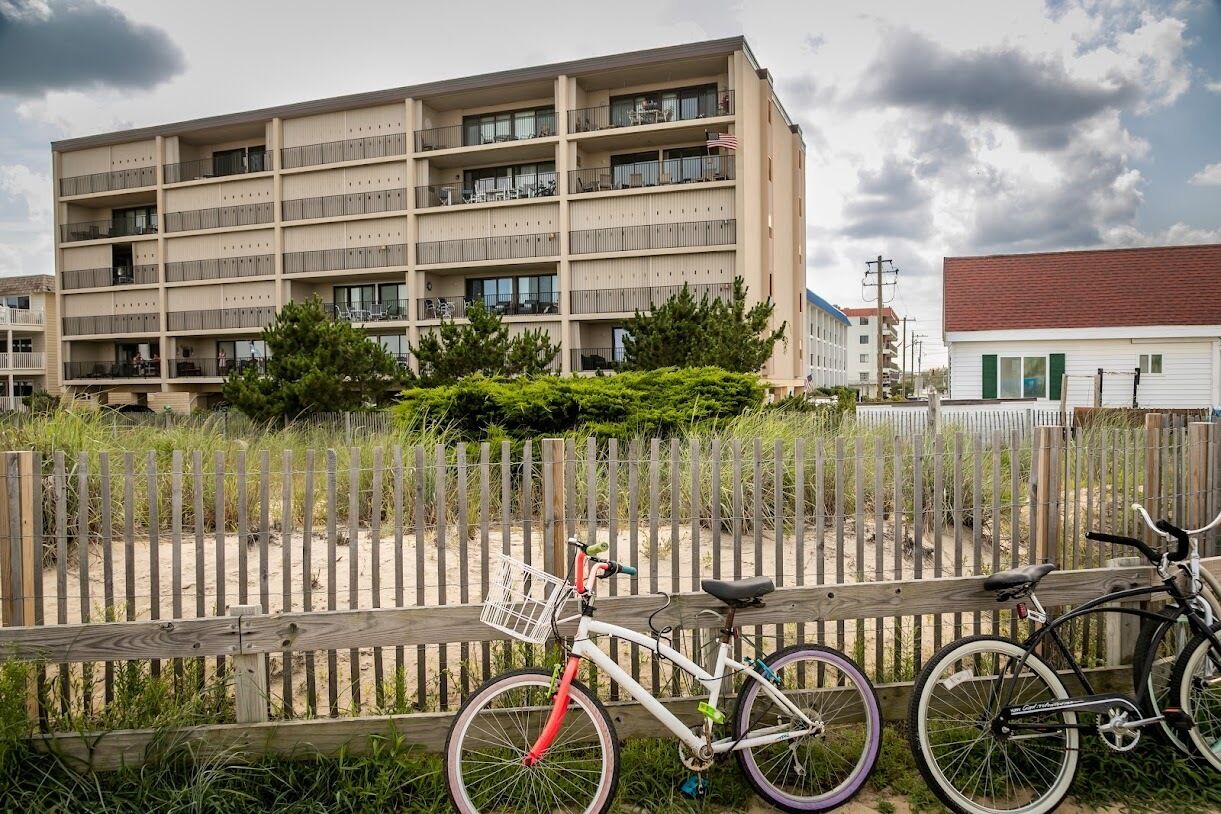 A multi-story building with balconies, a wooden fence, and a bicycle.