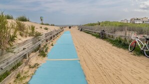 Un sendero en la playa con un tapete azul, una valla de madera y una bicicleta.