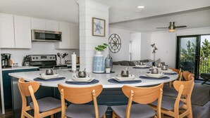 Una cocina moderna con armarios blancos, una isla central con taburetes altos, un microondas y una estufa.