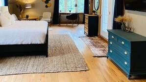 Um quarto com teto inclinado, uma cama, uma cômoda, uma escrivaninha e uma cadeira.
