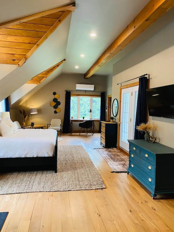 Une chambre avec un plafond en pente, un lit, une commode, un bureau et une chaise.