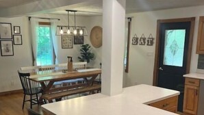 Cozinha moderna com ilha central, armários de madeira e área de refeições com cadeiras.