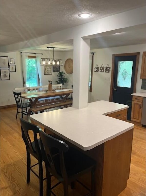 A modern kitchen with a central island, wooden cabinets, and a dining area with chairs.